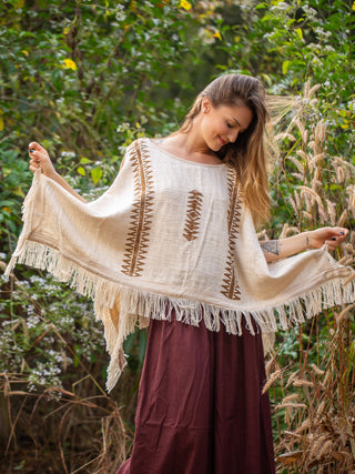 Natural cream Parvati cotton kimono held open to show the block print and fringe, garden backdrop