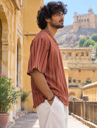 Rang Tee profile at a fort courtyard, raw fringed sleeve hem and striped cotton texture in view