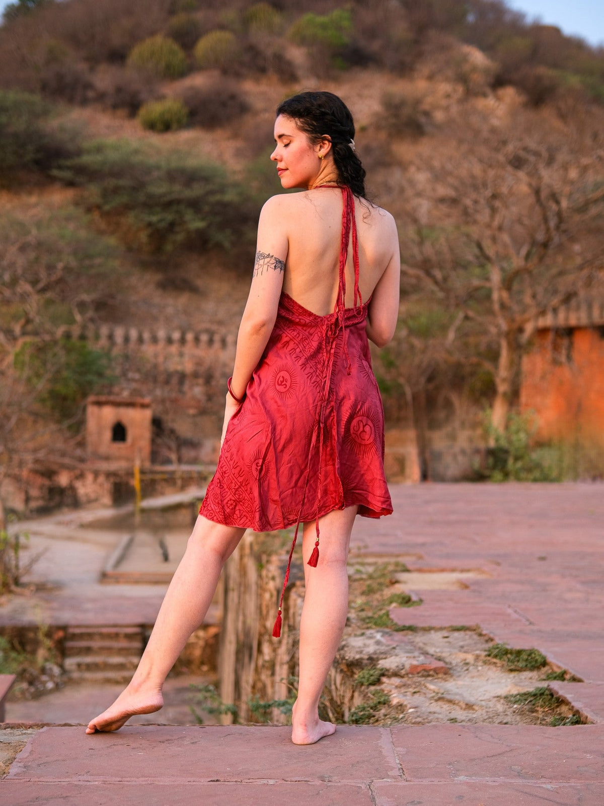 Back view of red halter dress showing deep V-back and long braided neck ties with tassels