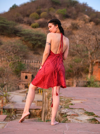 Full back view of red halter dress showing tasselled braided ties and flared hem