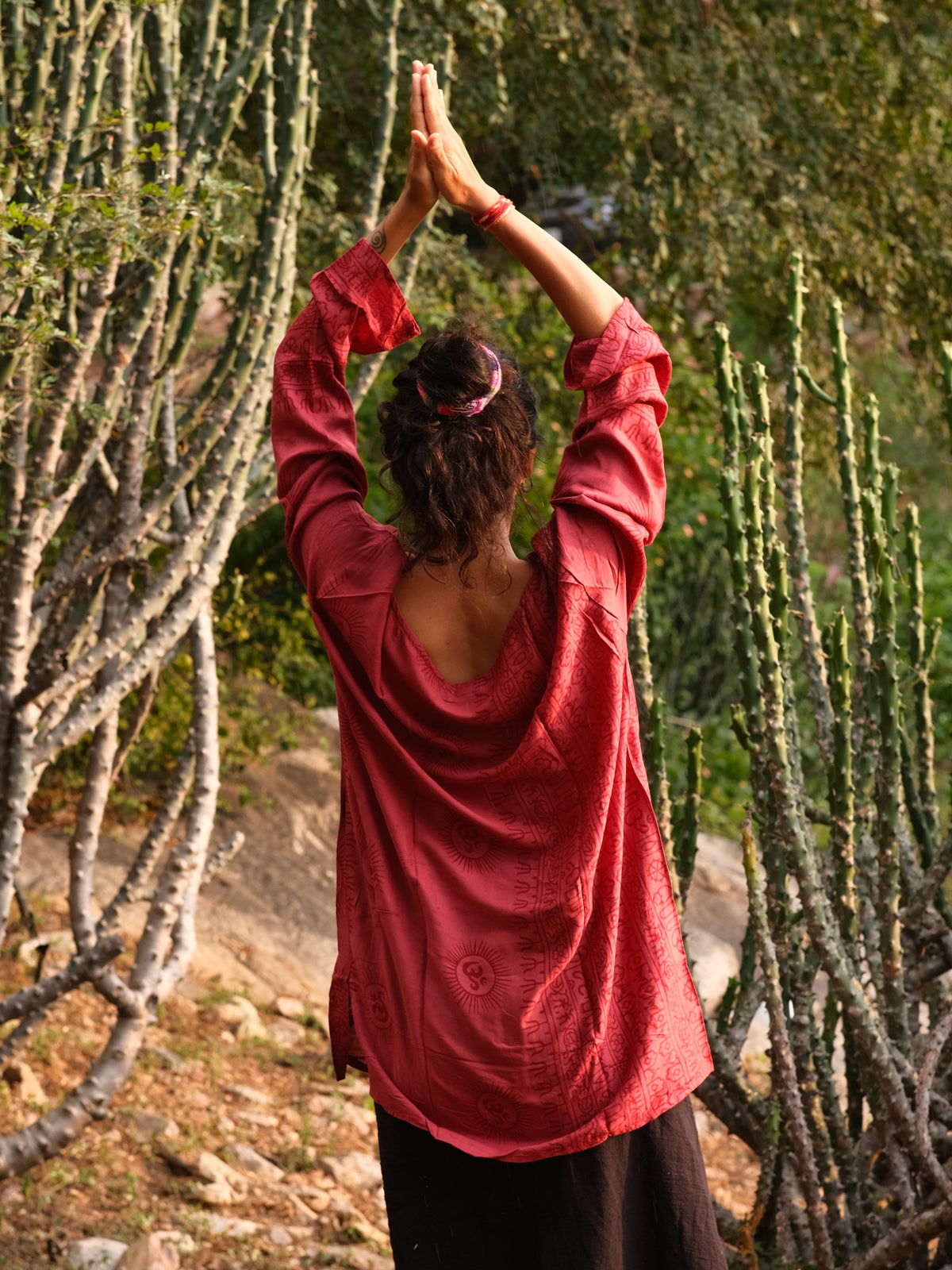 Back of the red Om print kurta with arms raised, medallions and hem border on the back panel