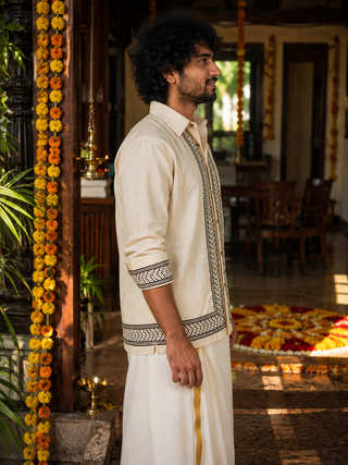 Side profile of cream embroidered shirt with black border and rolled-up sleeves