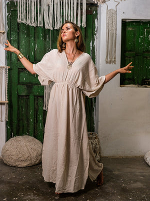 Rusalka Maxi Dress in natural khadi cotton, arms open front view in a green-door boho courtyard