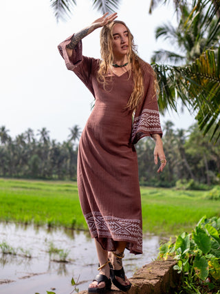 Samudra Maxi Dress brown cotton jute wide block print sleeve, side view in a paddy field