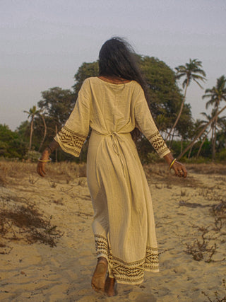 Samudra Maxi Dress natural cotton jute back view with tie waist, walking a beach at golden hour
