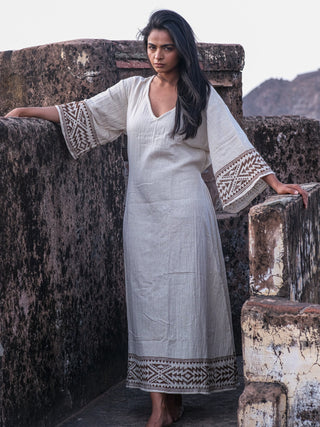 Samudra Maxi Dress natural cotton jute, model leaning on a fort parapet with printed sleeve