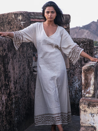 Samudra Maxi Dress natural cotton jute block print, model leaning on a fort stone wall