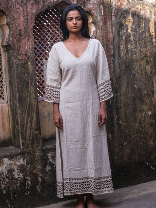 Samudra Maxi Dress natural cotton jute, model standing under a carved arch with printed hem