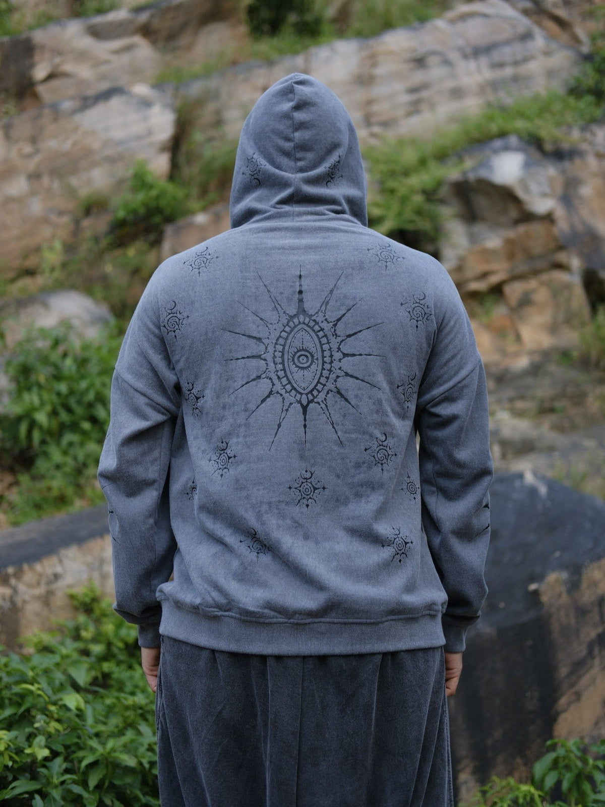 Back of the grey Shaam Hoodie showing the large sun eye graphic and scattered celestial motifs