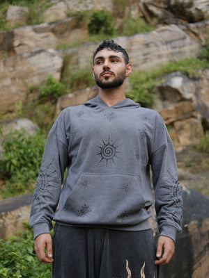 Grey Shaam Hoodie in cotton fleece with celestial sun print on the chest, worn by a model outdoors