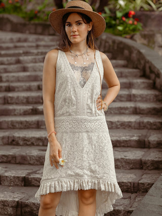Front view of the Surekha white lace cotton dress with its lace waistband, worn on stone steps