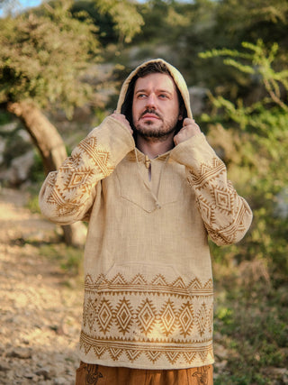 Sand yellow handblock hoodie with black tribal print, hood up, model adjusting drawstring