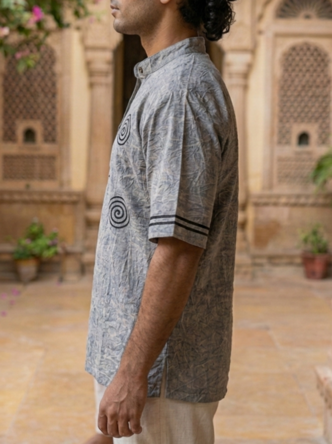 Close side view of the grey Tribal Japanese Shirt, spiral-sun motif on the front panel and striped sleeve band