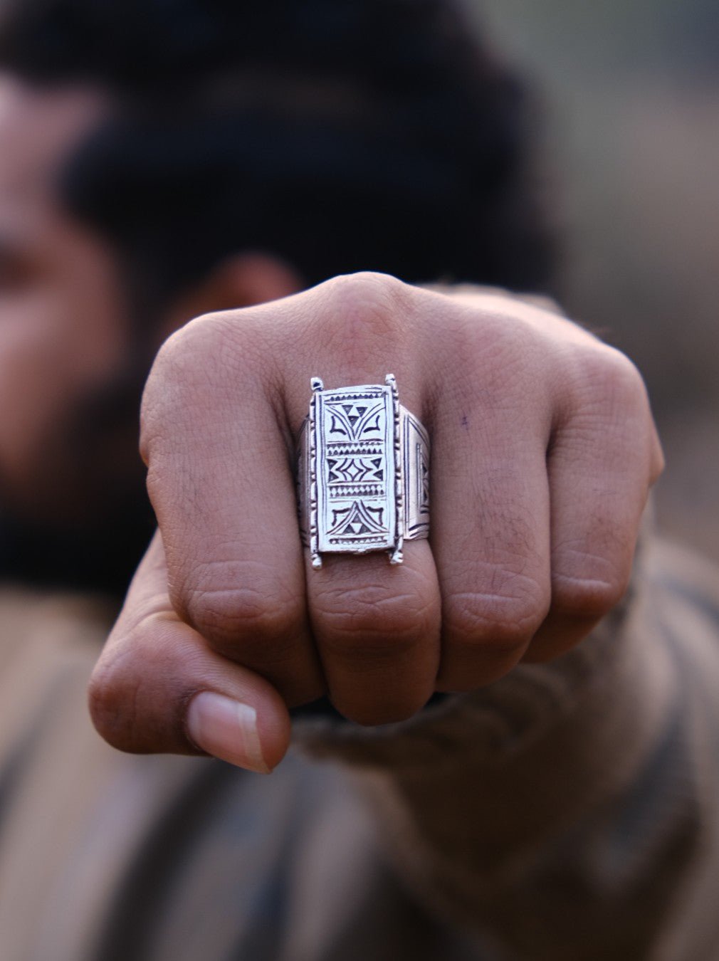 Tuareg nickel silver ring worn on a man's clenched fist, engraved tribal panel facing forward