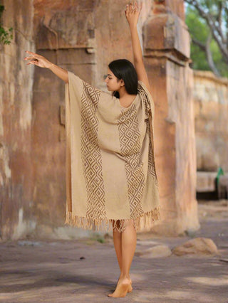 Beige hand block printed kaftan dress with tassel hem, full front view at Rajasthan stone archway