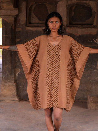 Tula kaftan in terracotta brown hand block print cotton, model with arms wide at heritage temple ruins, free-size boho dress