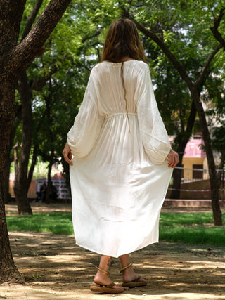 White balloon-sleeve maxi dress back view under neem trees