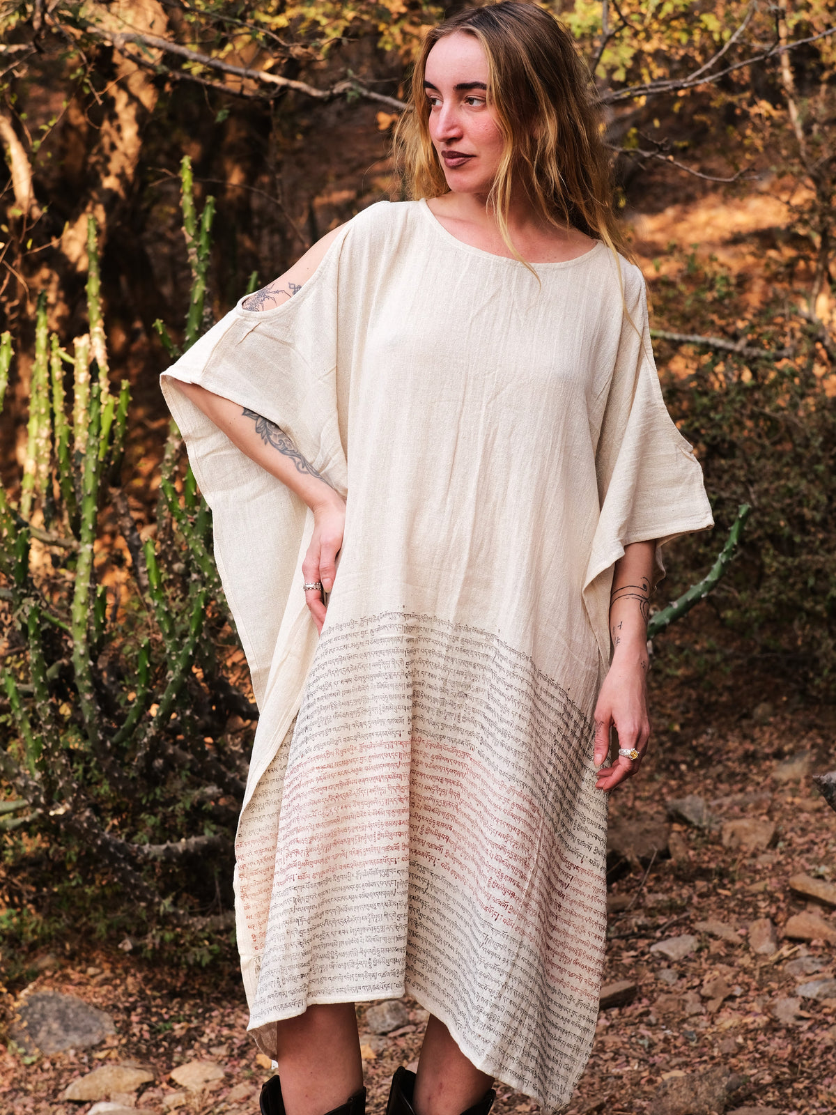 Yaja Kaftan in undyed hand block print cotton worn loose, one arm raised, in desert scrub