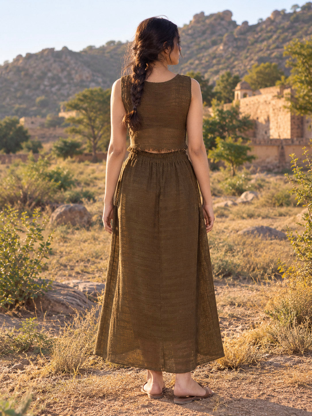 Back view of the brown long cotton Zarra skirt, showing the full A-line sweep and gathered waist, hills beyond